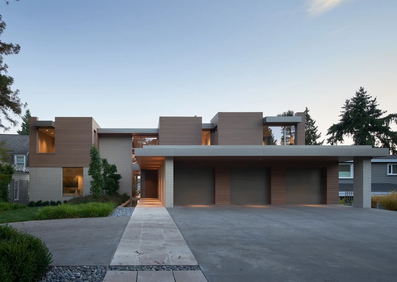 Union Bay Residence features a modern exterior with wood siding and brick, including a three-car garage and flat roof elements.