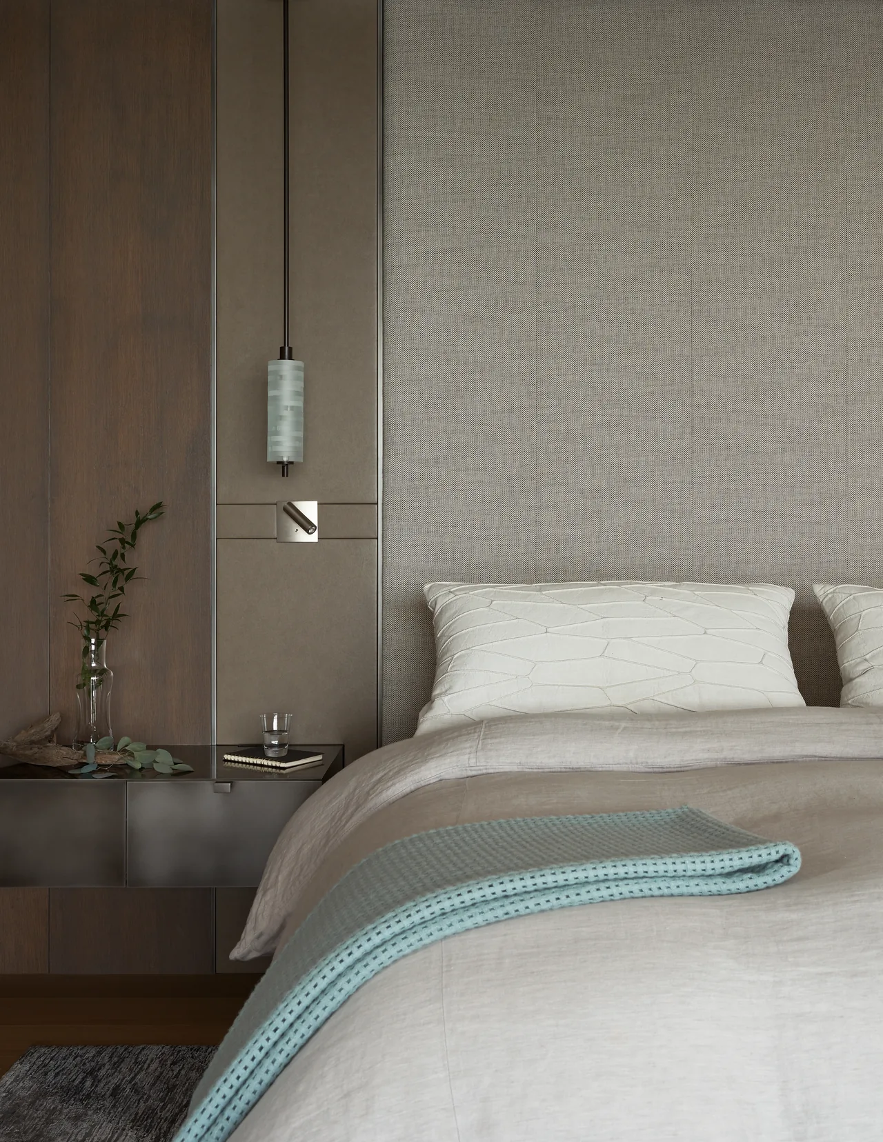 Bedroom corner features a textured wall, floating nightstand, and a cylindrical pendant light over the bed.