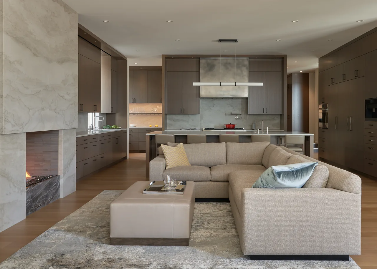 Open-plan living room and kitchen with wood cabinetry and a large beige sectional sofa at Union Bay Residence.