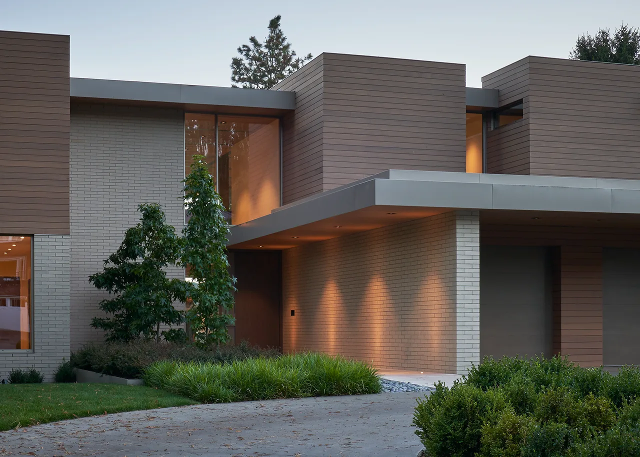 The Union Bay Residence features a modern exterior combining white brick and horizontal wood siding with a flat roof and large windows.