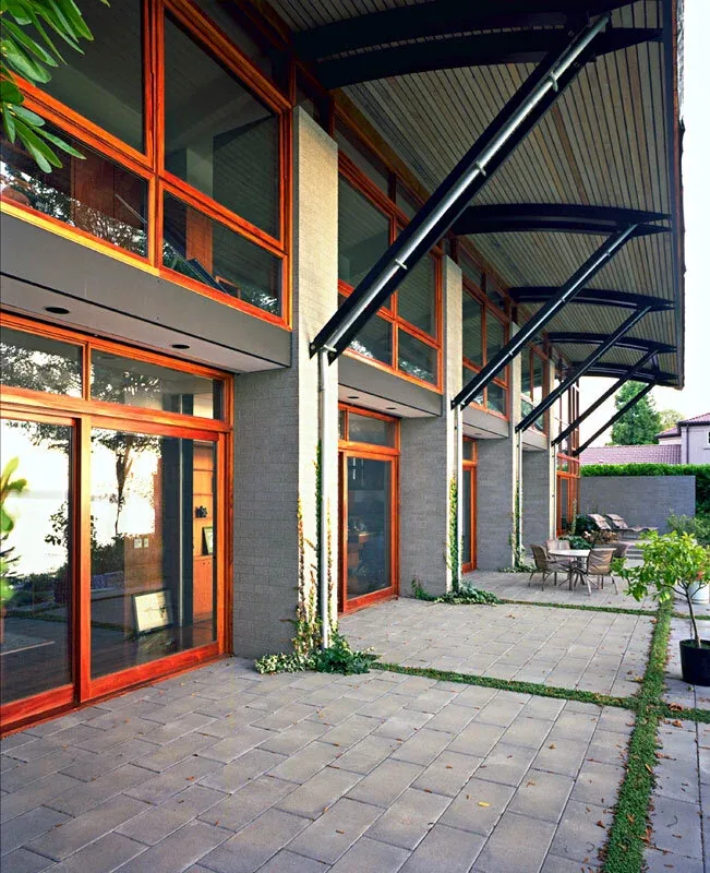 The Solbeck Residence features large wood-trimmed windows and a curved roof over its outdoor patio area.