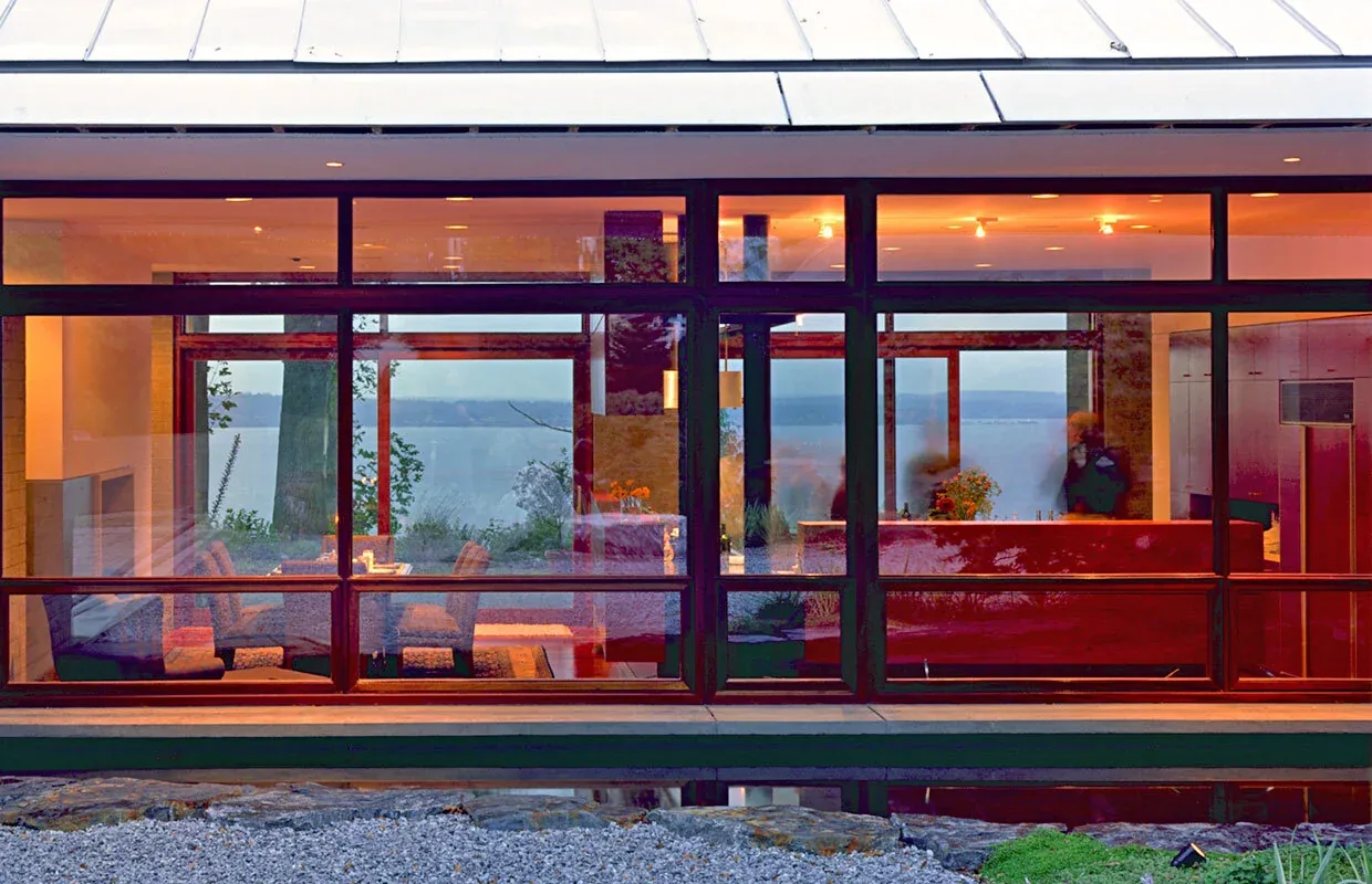 The Solbeck Residence features large steel structural supports and sliding glass doors overlooking a natural landscape.