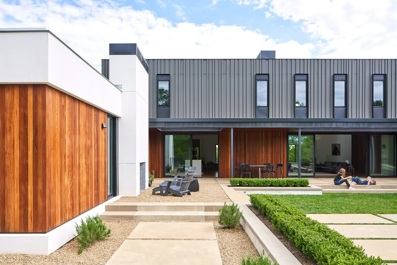 Calloway Ridge House features wood and metal siding with vertical windows and a landscaped courtyard with seating.