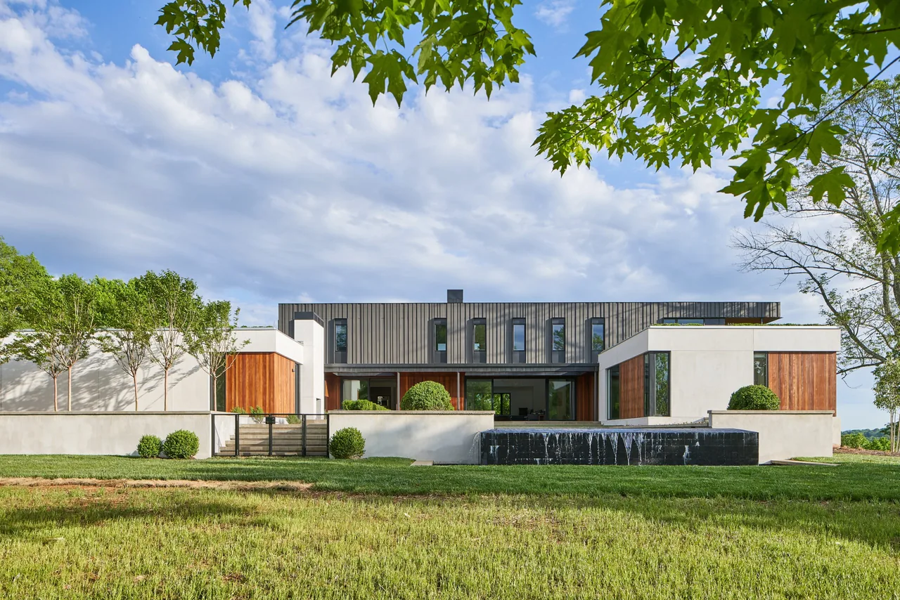 Exterior front view of Calloway Ridge House showing white walls, wood panels, vertical windows, and a reflecting pool water feature.