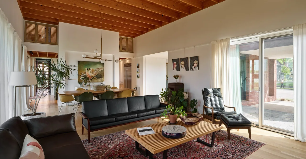 Living and dining space at Morgan Street House featuring black leather seating and large sliding glass doors to the exterior.