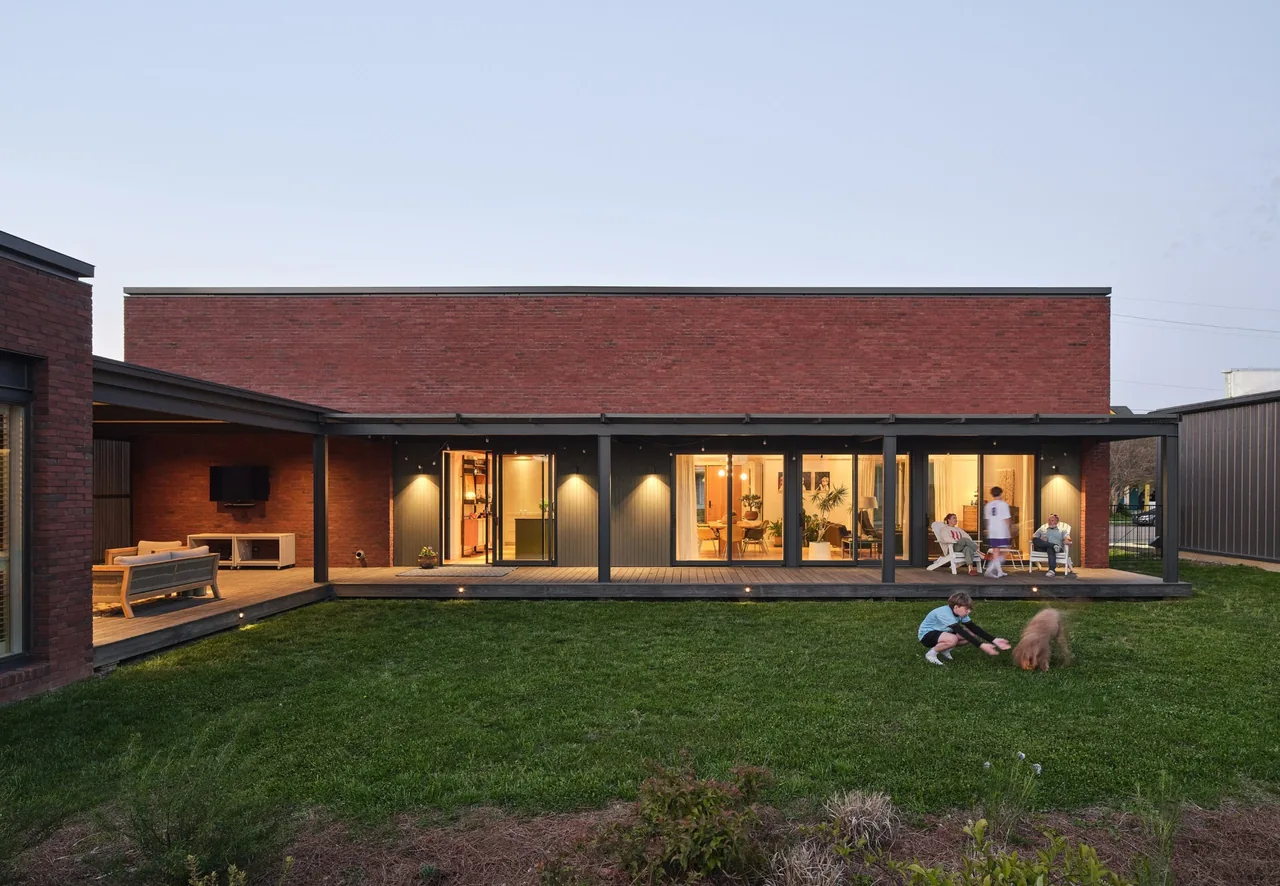 Morgan Street House features a flat roof brick exterior with a covered porch and lawn area where residents relax and play.