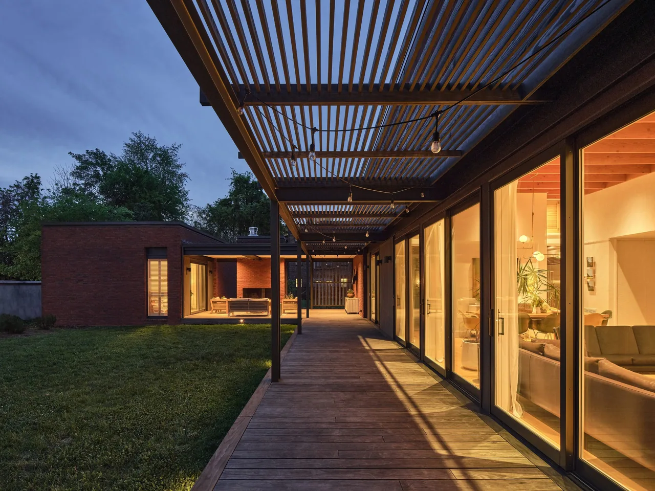 The Morgan Street House features a wooden deck patio with a slatted pergola and large glass doors opening to the living space.