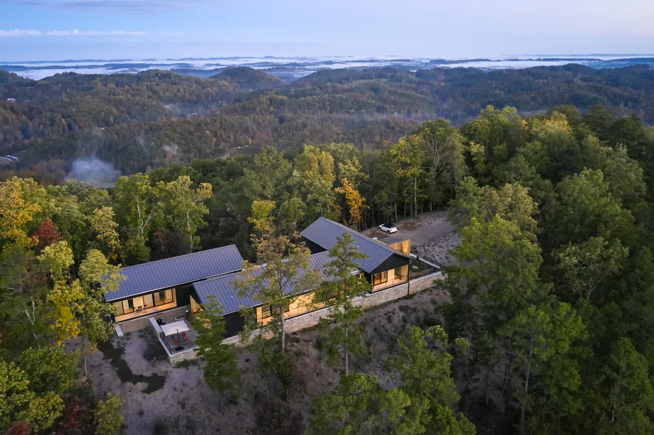 Short Mountain House by Sanders Pace Architecture is nestled in a wooded setting with connected volumes and metal roofs.