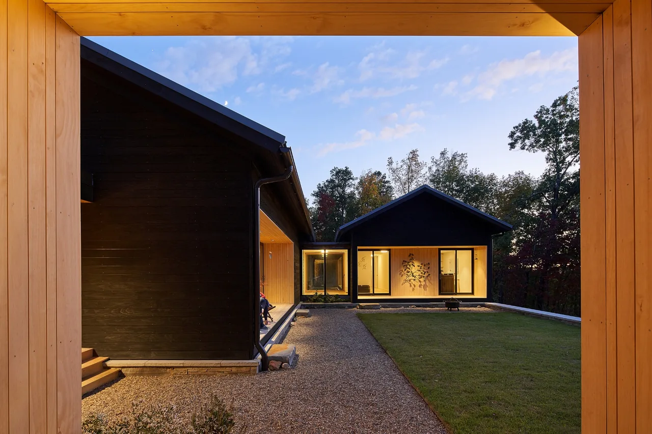 Short Mountain House features a black wood exterior with connected volumes forming a courtyard framed by wooden elements.