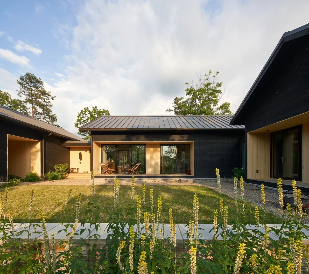 Exterior courtyard of Short Mountain House features black wood siding contrasted with natural wood accents and metal roofing.