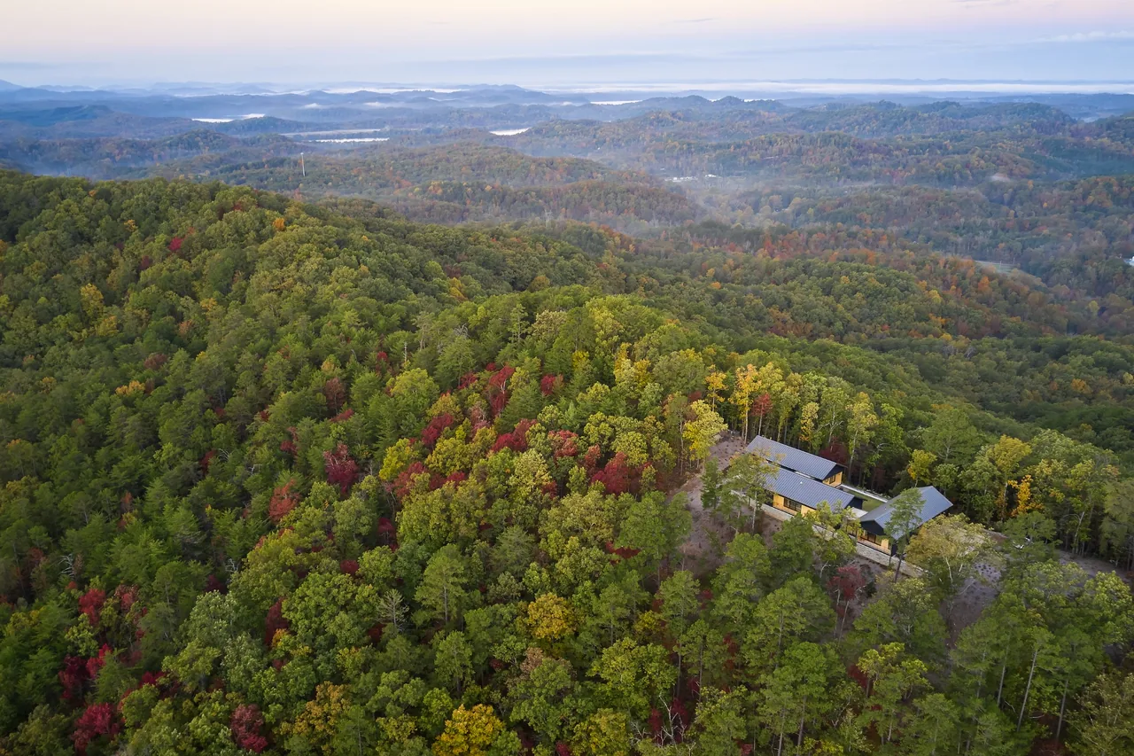 The Short Mountain House by Sanders Pace Architecture sits secluded among forested mountains with fall foliage hues.