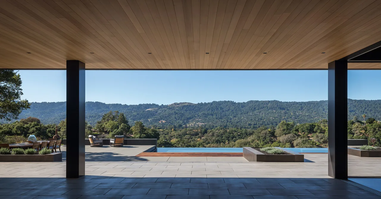 Portola Valley House outdoor living area with a covered patio and pool, showcasing views of forested hills.