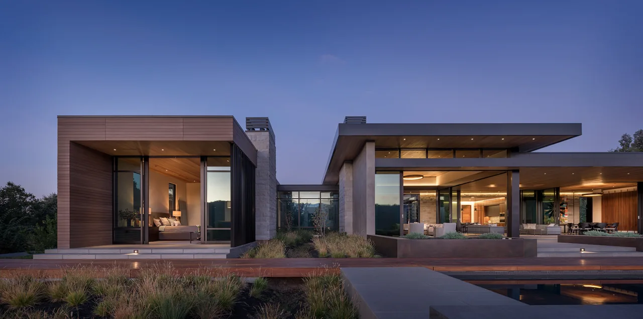 The Portola Valley House by SB Architects showcases a modern flat roof and extensive glazing overlooking an outdoor seating area and pool.
