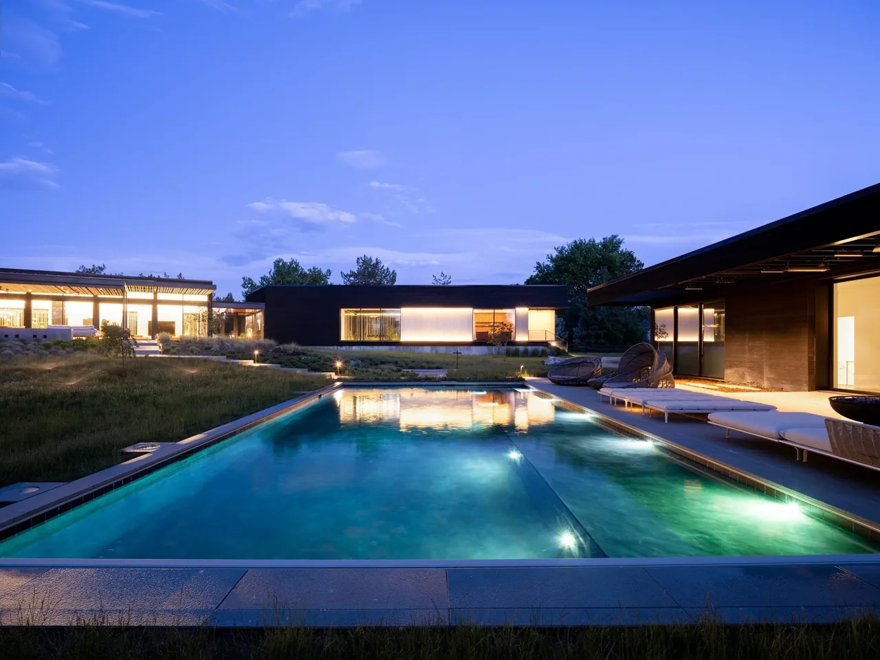The Hunter Residence features a modern exterior with a rectangular swimming pool and outdoor lounge seating.