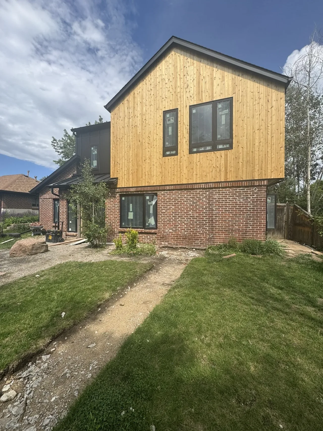 Two-story house exterior with a combination of brick and vertical wood siding under a gable roof.