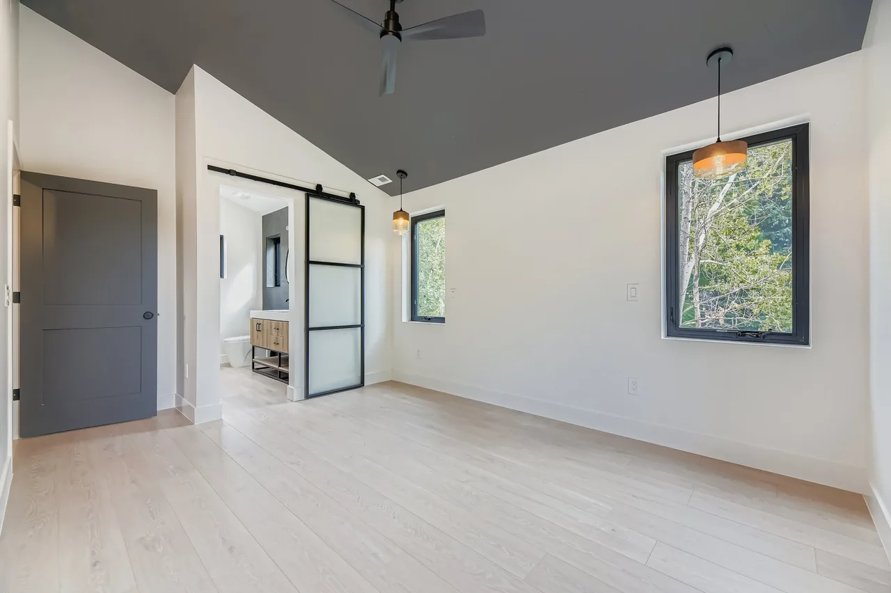 This modern bedroom has a distinctive gray ceiling and frosted glass barn door leading to the bathroom.