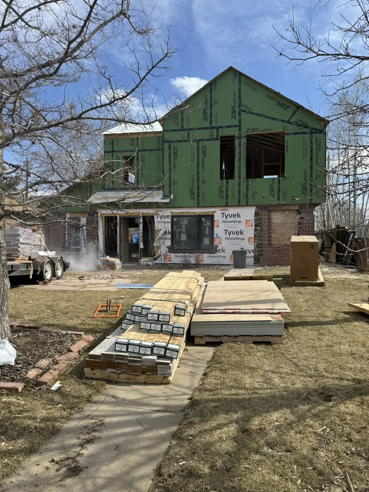 Two-story house in mid-construction with green ZIP system sheathing and brick lower exterior walls