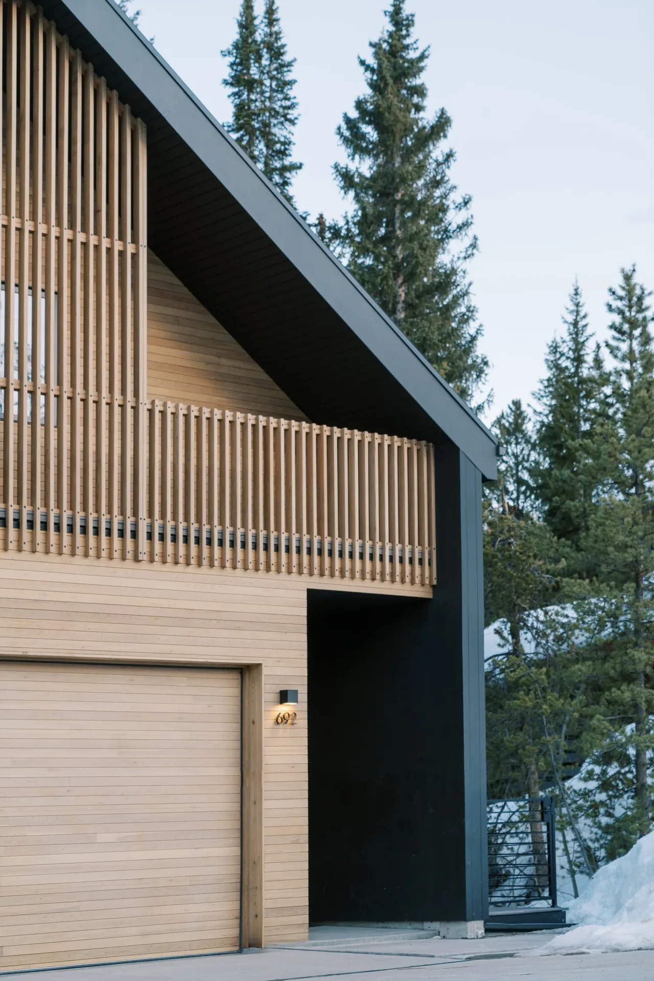 Winter Park Residence features light vertical wood siding with a distinct balcony railing and a dark gable roof edge.