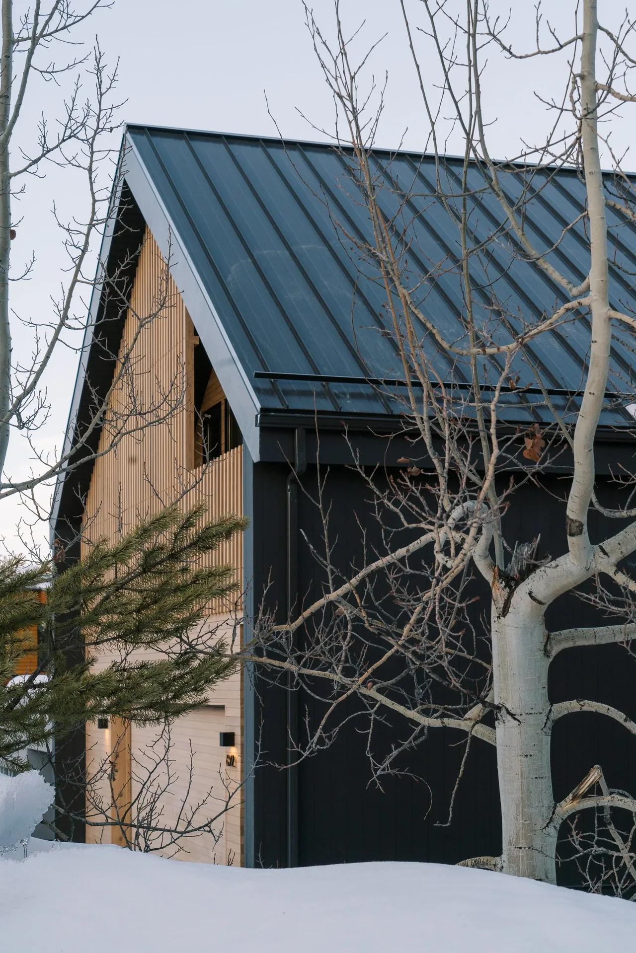Winter view of the residence showing its metal standing seam roof and wooden vertical siding detail.