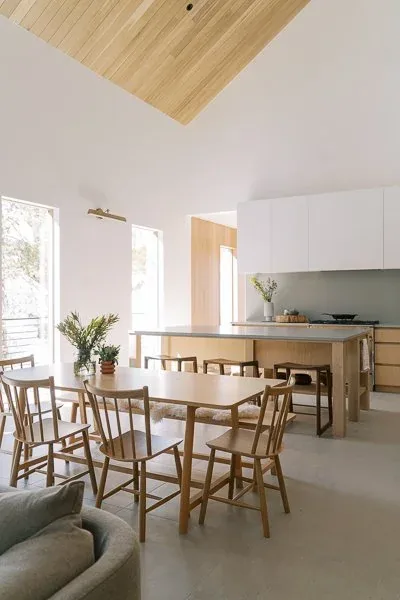 WINTER PARK RESIDENCE dining and kitchen area features wood furniture, a sloped wood ceiling, and high windows providing natural light.