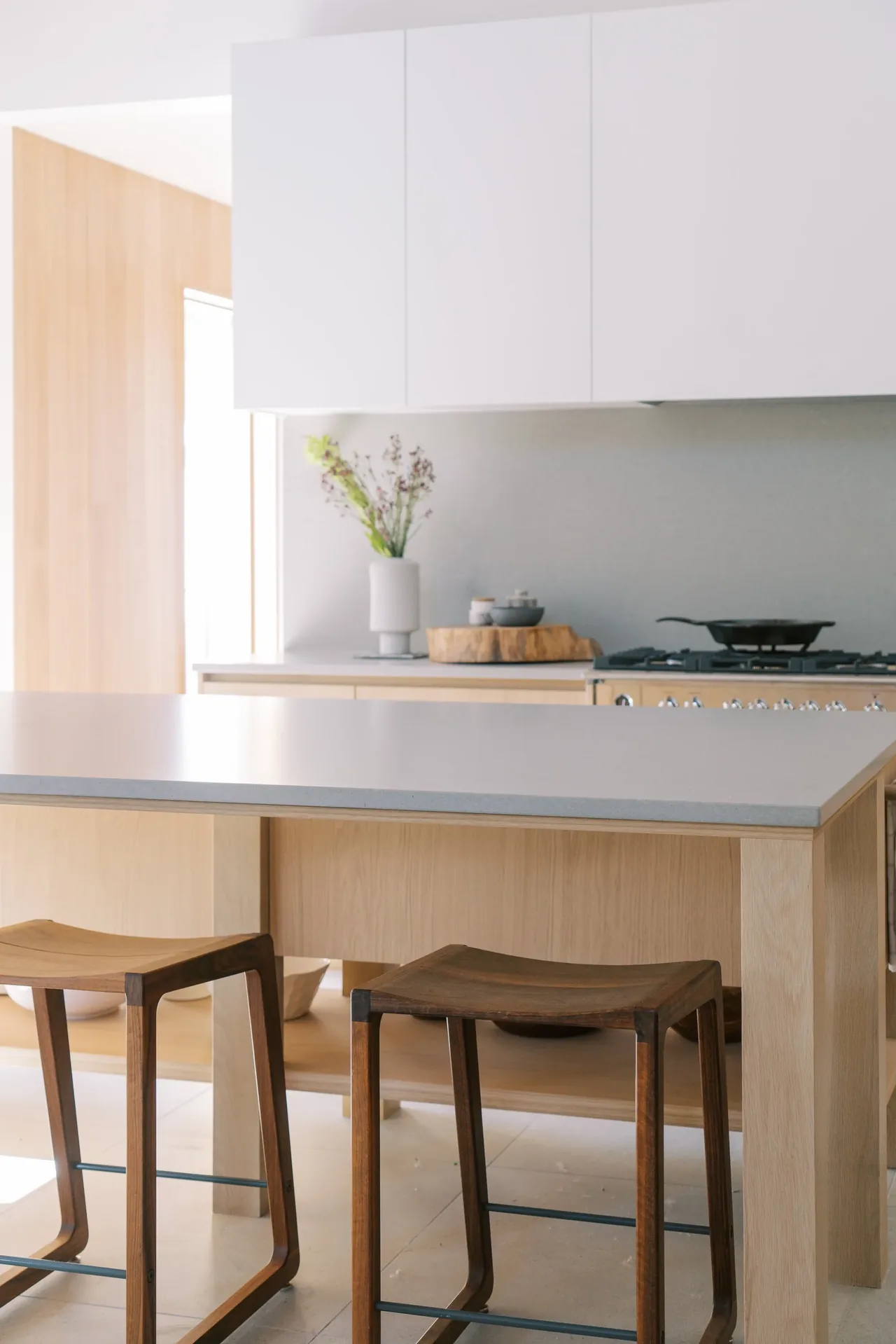 Modern kitchen featuring a light wood island with wooden stools and white upper cabinetry.
