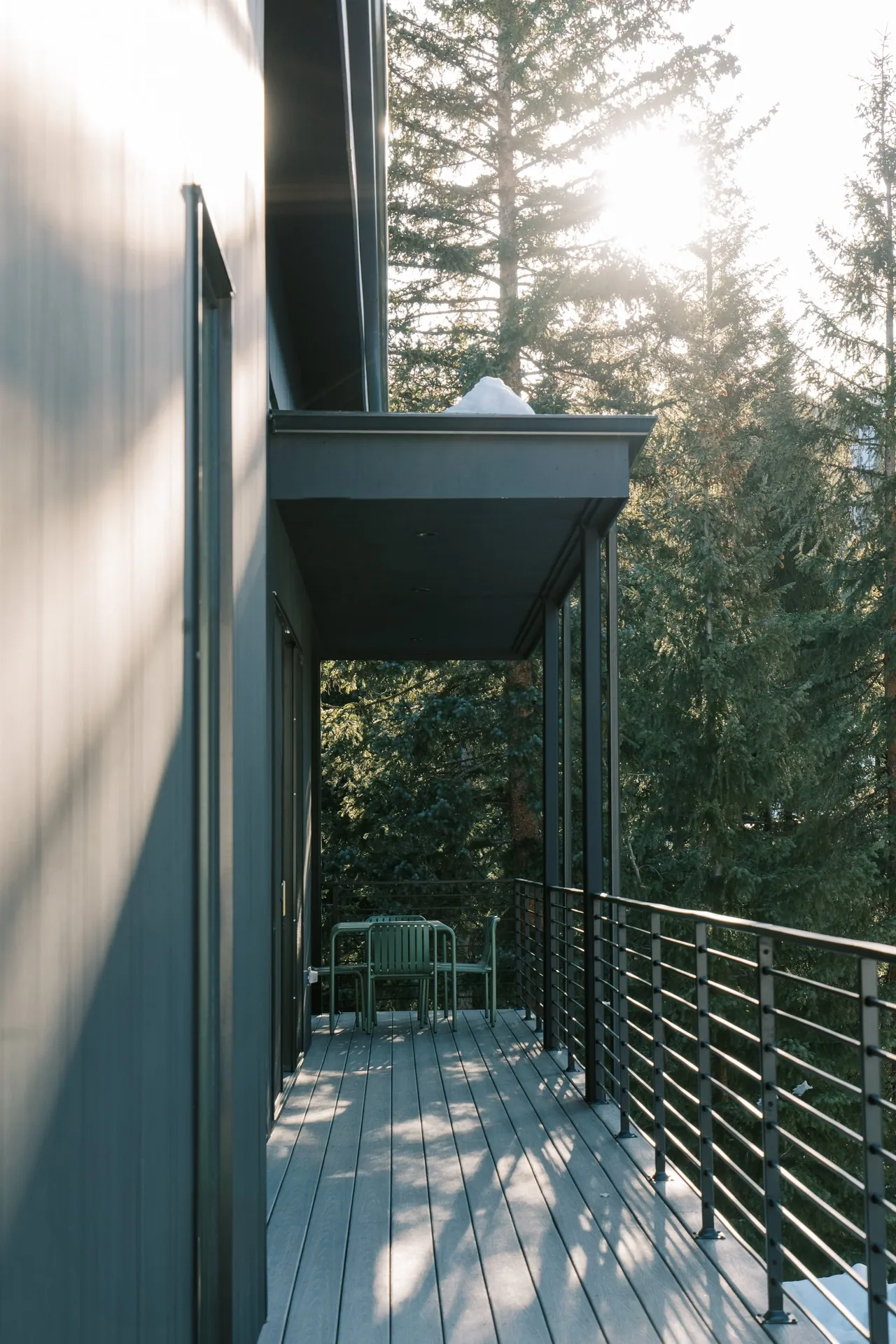 Balcony with metal railing and outdoor seating looking out to a forested area in WINTER PARK RESIDENCE.