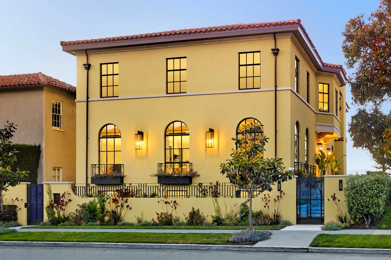 Seacliff Residence featuring a yellow stucco exterior, terracotta roof tiles, and arched windows with black frames.