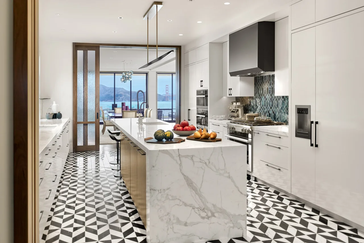 Seacliff Residence kitchen features a large marble island, patterned tile floor, and panoramic bay views.