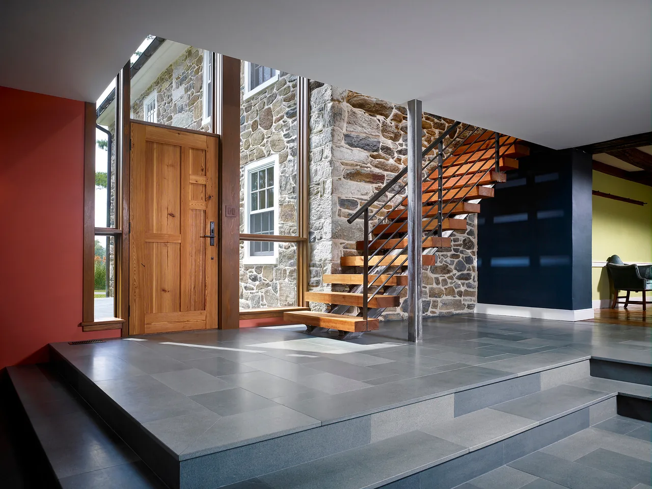 Entryway with stone wall and floating staircase in Elverson Addition by Wyant Architecture.