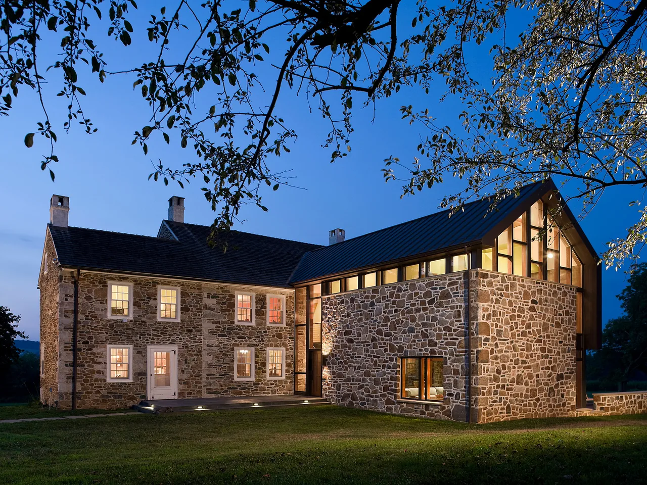 The Elverson Addition features a historic stone facade with a modern metal roof and extensive glazing at dusk.