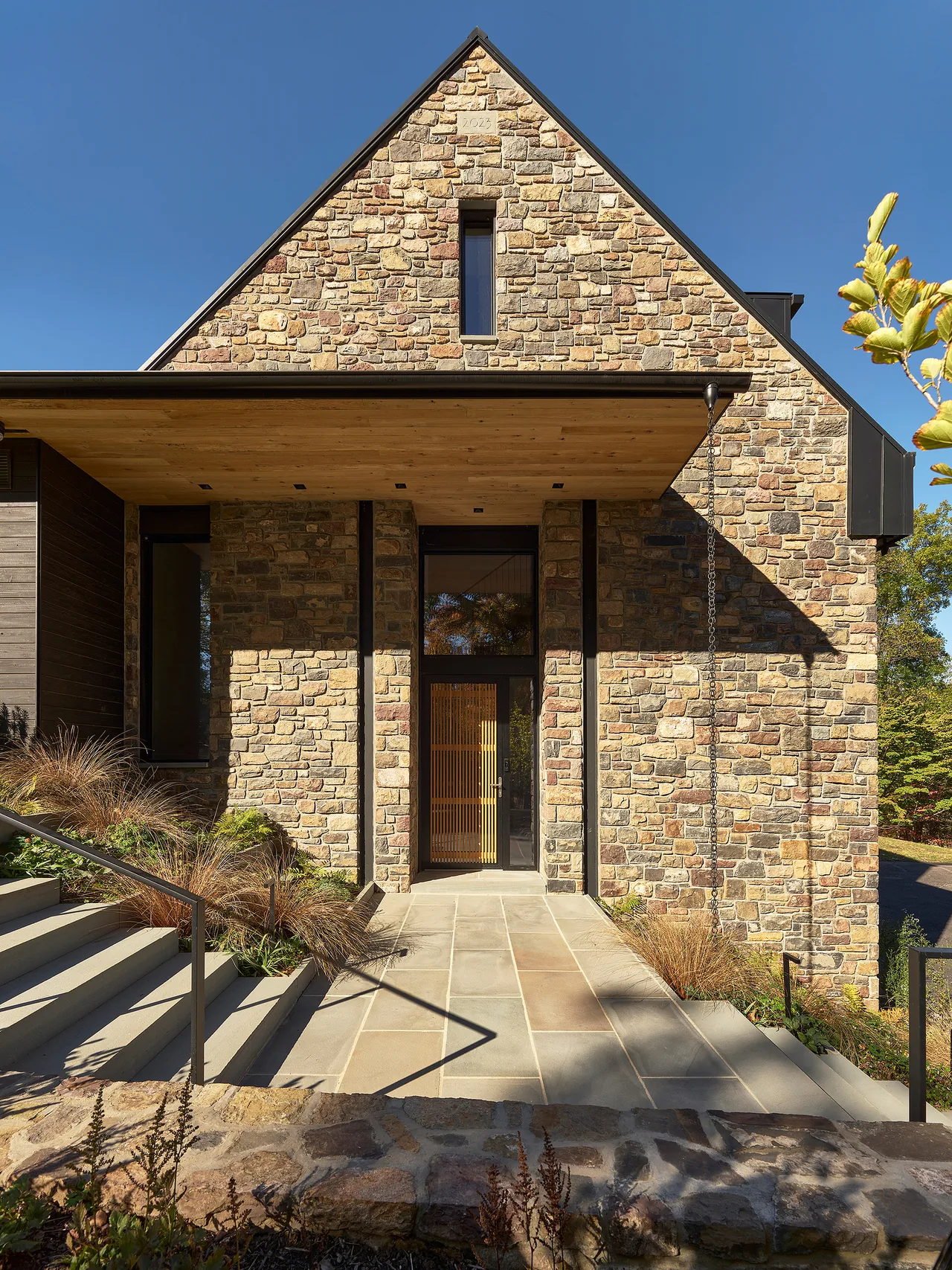 The Bucks Retreat features a stone exterior with a gable roof and a covered entry with wood ceiling under Wyant Architecture.