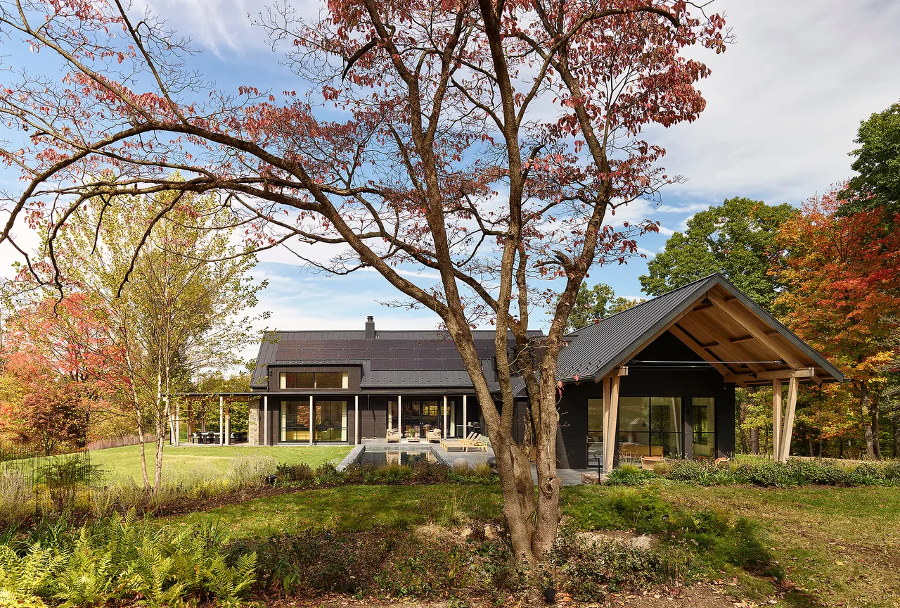Bucks Retreat features a dark facade with a steep gable roof and natural wood accents, surrounded by landscaped greenery.
