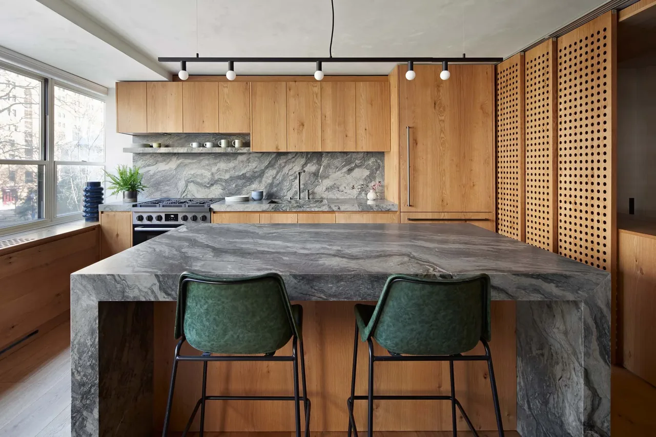 Kitchen featuring a black stone countertop island with wood cabinetry and perforated wood panel screens by Lo Design.