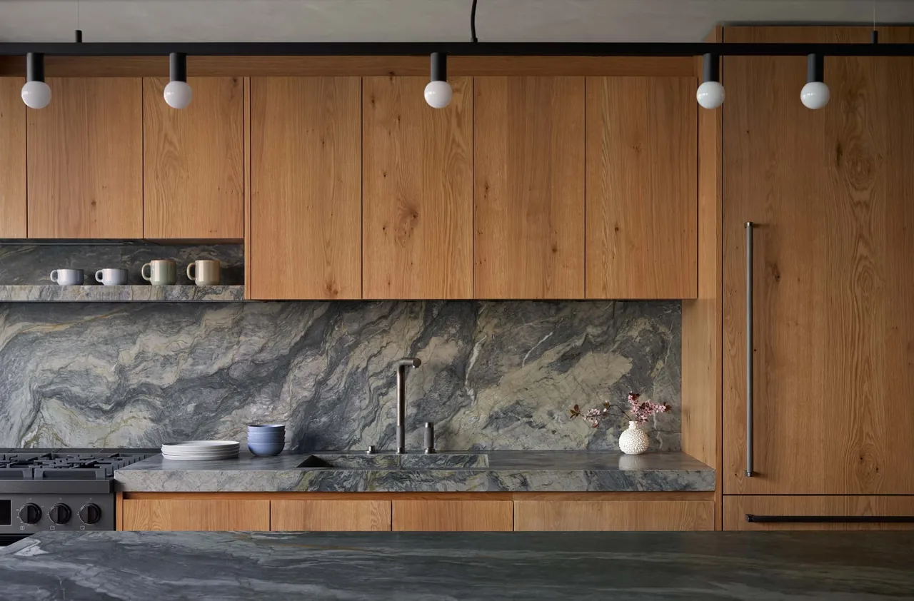 Kitchen featuring wood cabinets and a distinctive dark stone countertop and backsplash with a modern black track lighting.