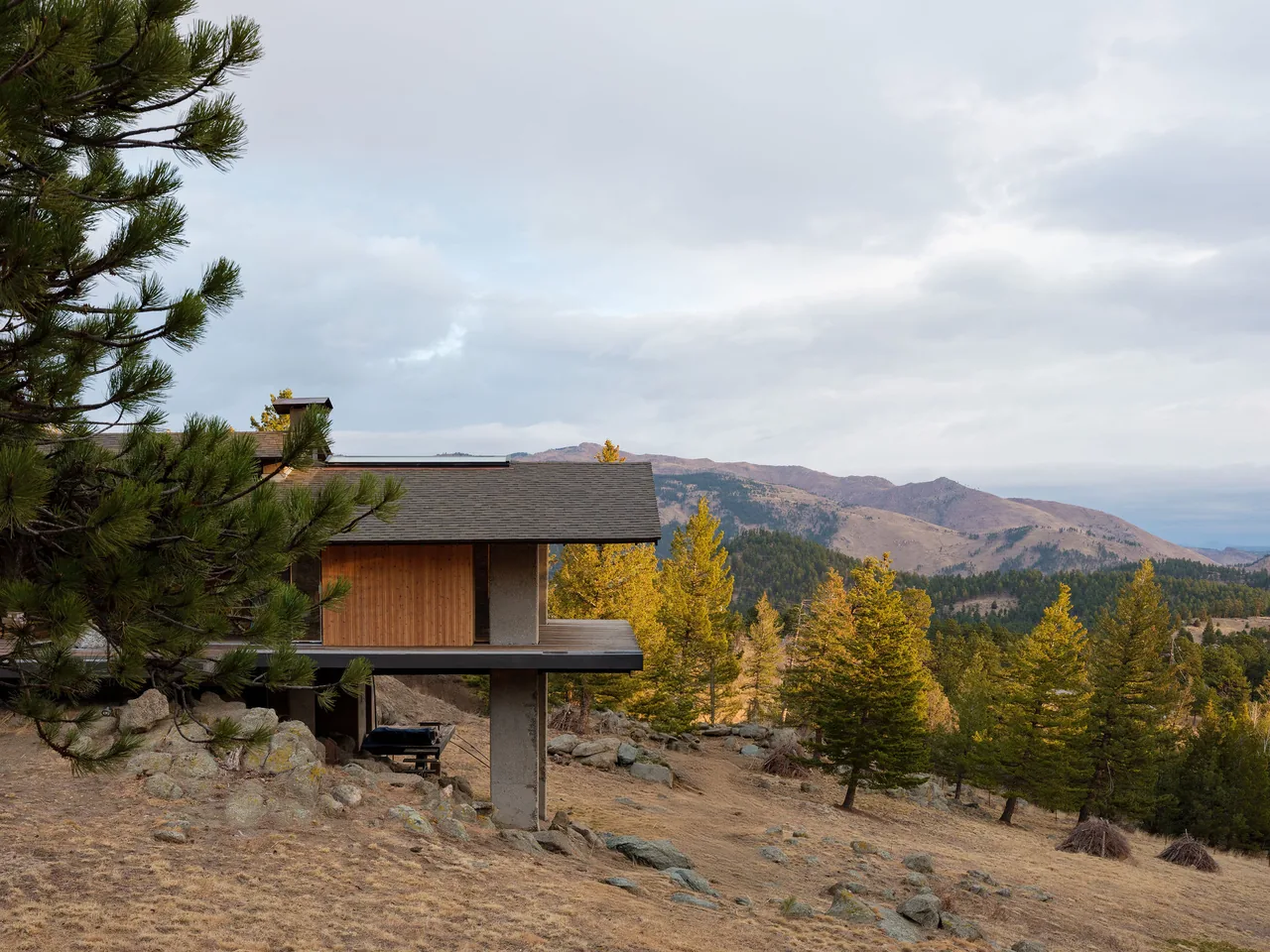 Sentinel Rock house features a wide roof overhang and natural wood siding, blending with the rocky landscape.