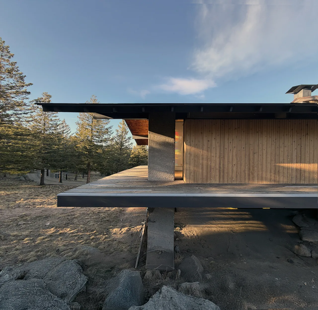 Sentinel Rock features a flat roof with wide overhangs supported by concrete pillars and vertical wood siding.