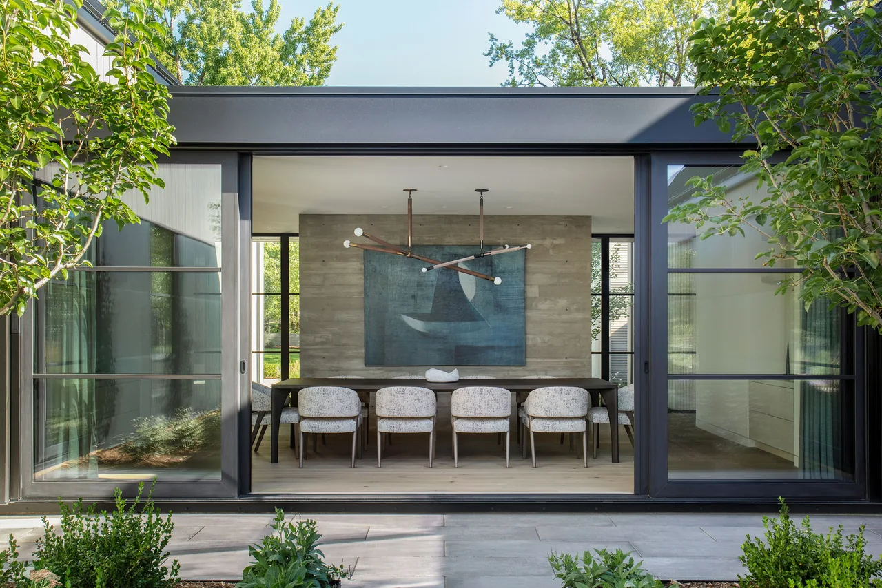 The dining room at Linden Grove features floor-to-ceiling sliding glass doors and a concrete accent wall.