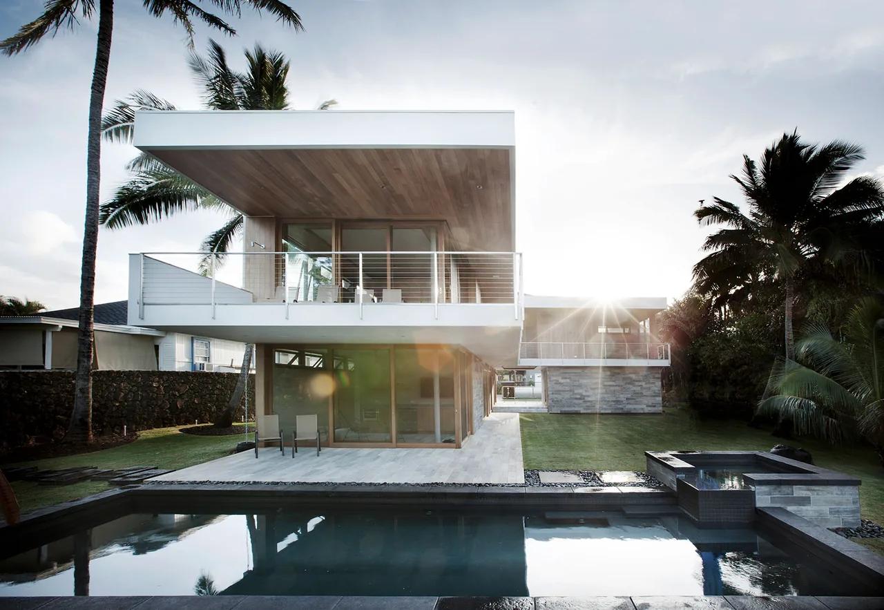 Island House by Piché Architecture features a cantilevered second floor and an outdoor pool area with tropical landscaping.