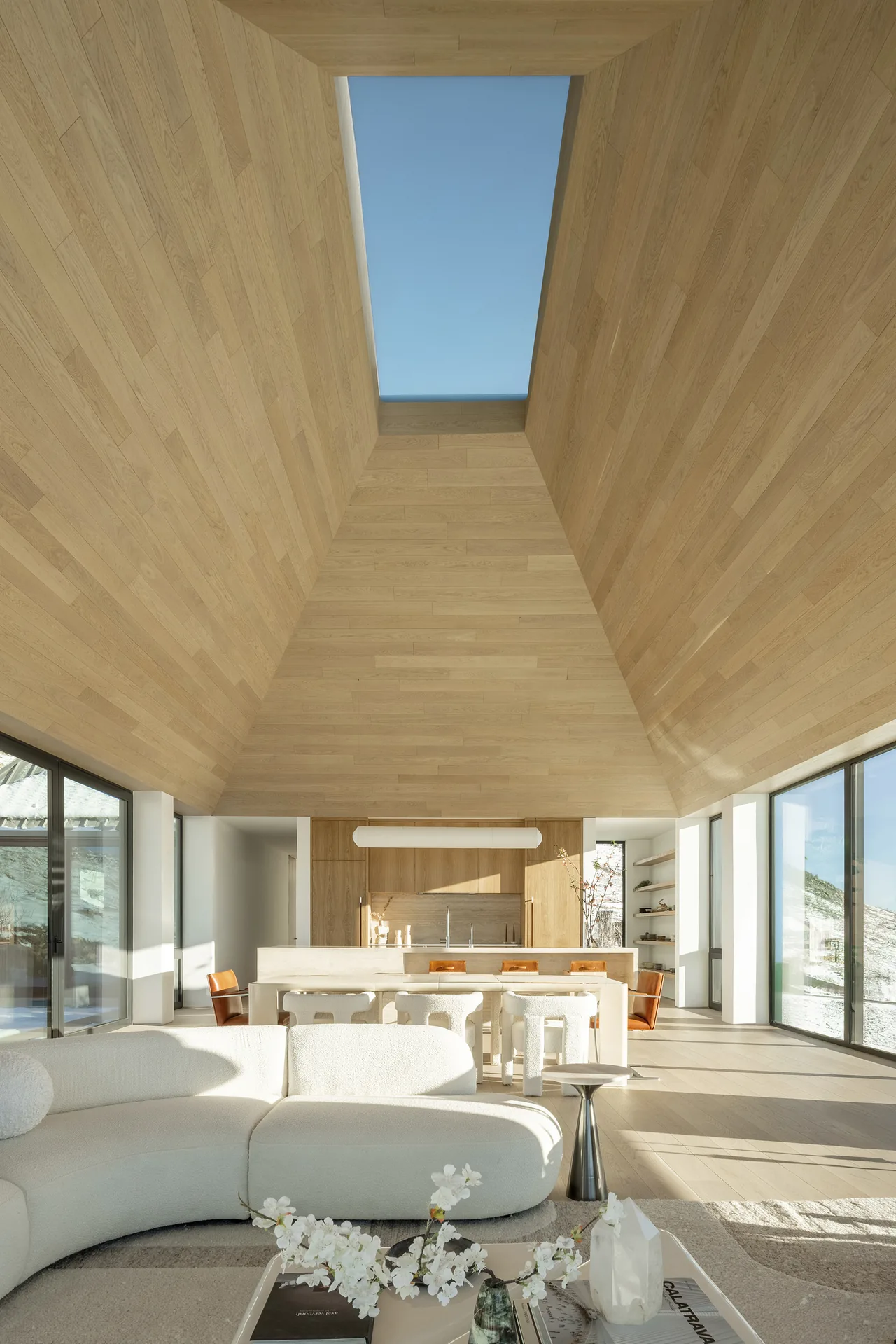 Open plan living and kitchen with a vaulted wood ceiling and skylight in Mountain Ridge project by Piché Architecture.