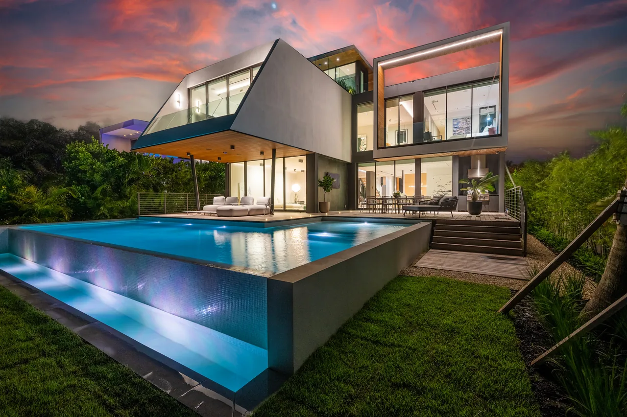Exterior rear view of Venetian Island I featuring an infinity pool and cantilevered upper floor with large glass windows.