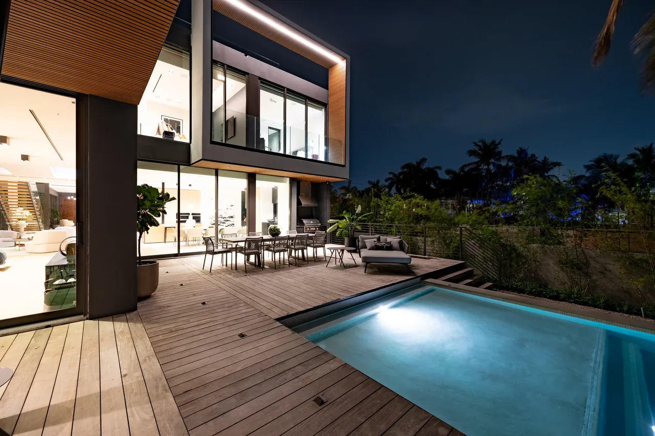 Venetian Island I features a modern exterior with a wooden deck patio and illuminated pool at night.