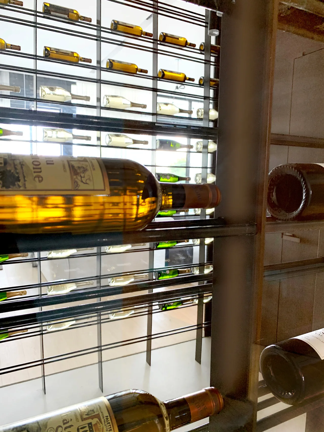 Wine display wall showcasing horizontally stored bottles with metal racks in an interior space.