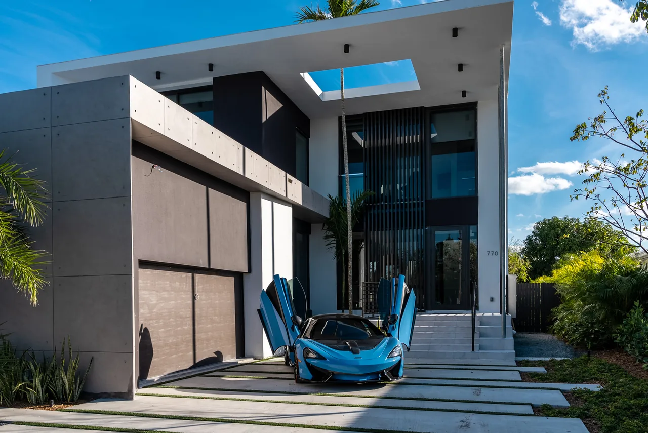 Exterior front view of Normandy Island S.Shore I showing concrete and white walls with black window frames and a car with butterfly doors in the driveway.