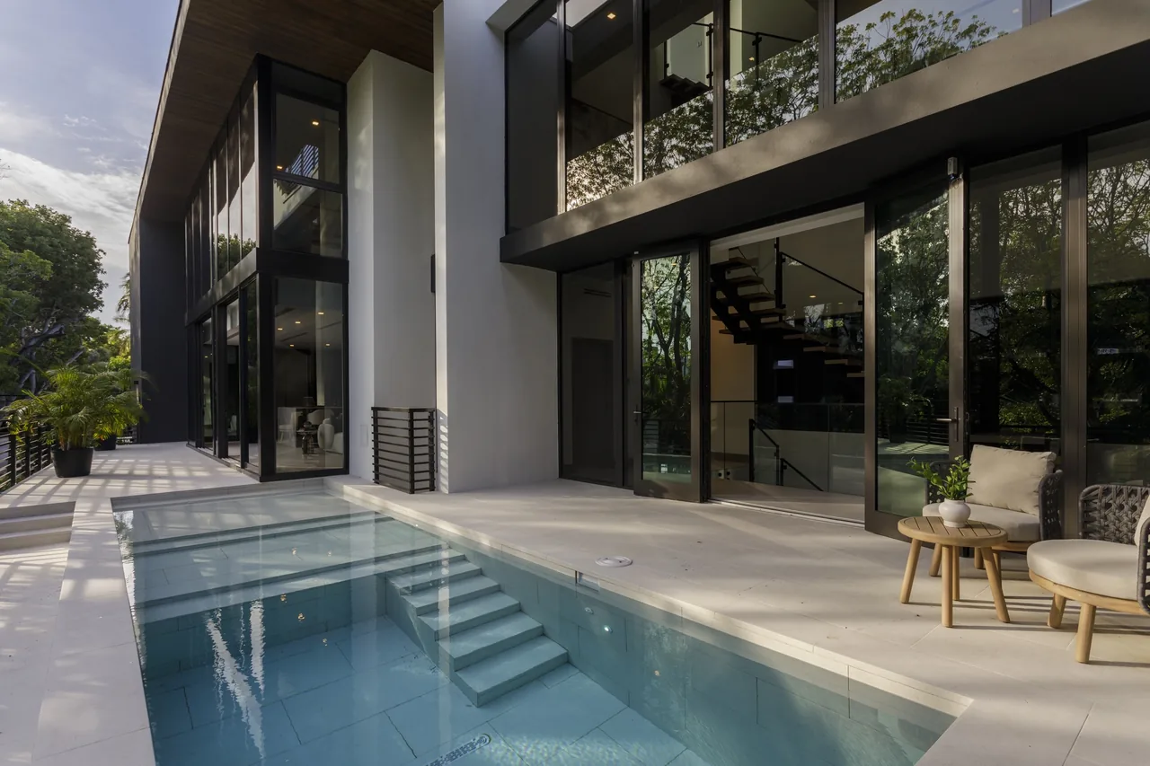 WILTON HOUSE features floor-to-ceiling glazing and a small pool adjacent to an outdoor seating area on the terrace.