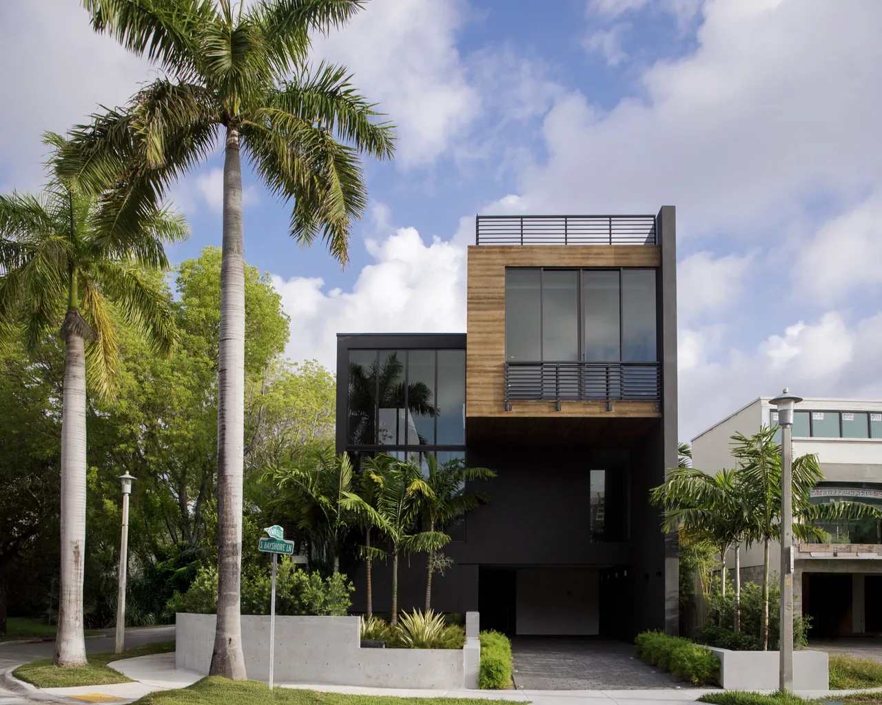 Fair Isle Residence features a modern style with black walls and a cantilevered wooden top floor box with large windows.