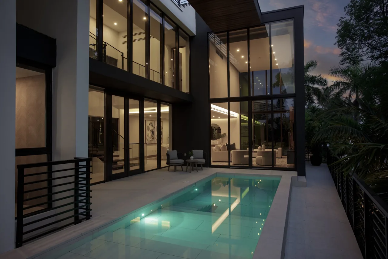 Fair Isle Residence features large floor-to-ceiling glazing opening to a rectangular pool from the patio and living areas.