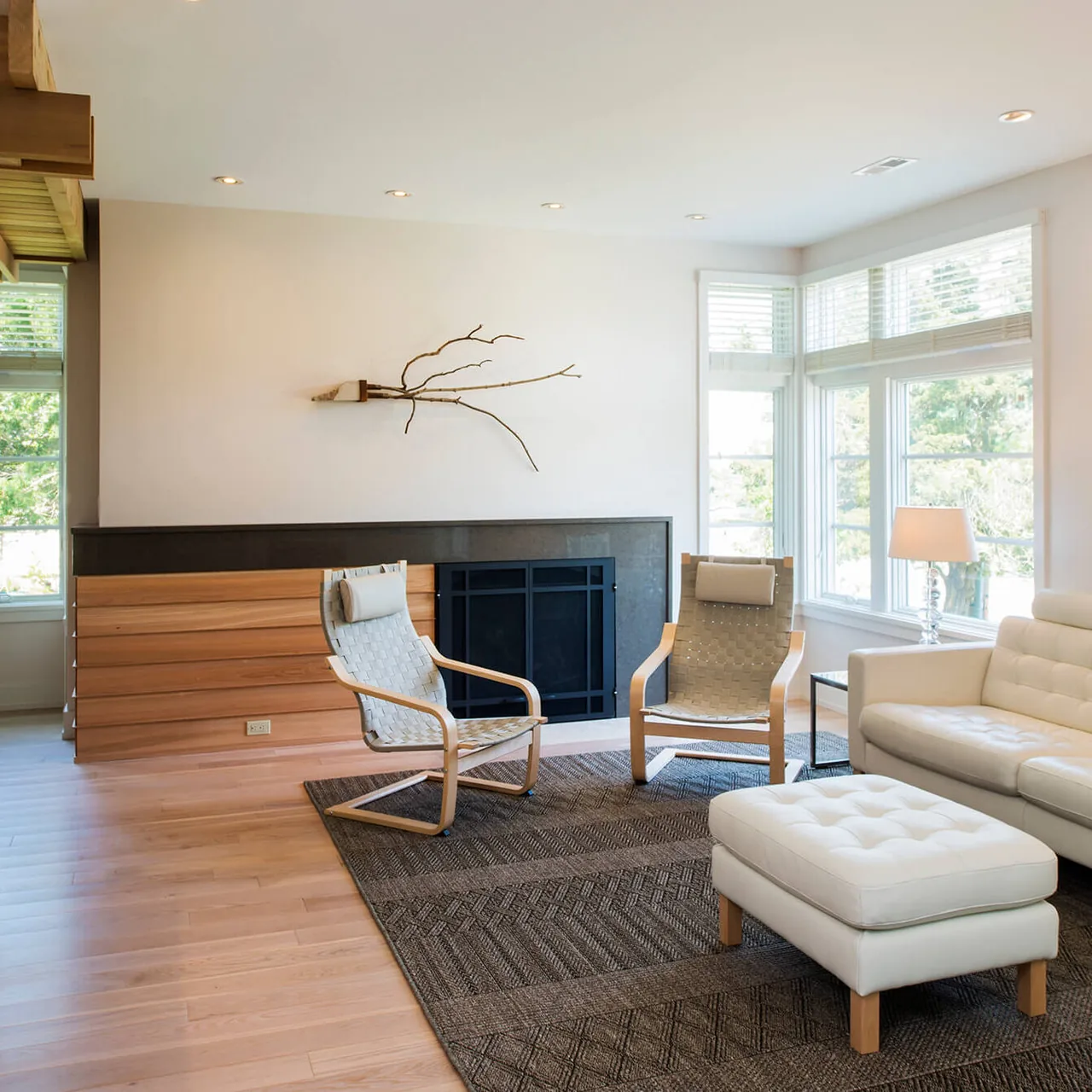 The Prospect House living room features wood floors, a fireplace with wooden paneling, and large windows that provide ample natural light.