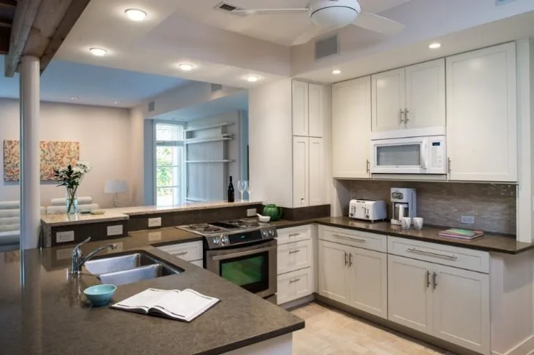 Kitchen features white cabinetry, gray countertops, and stainless steel appliances including a range and microwave.