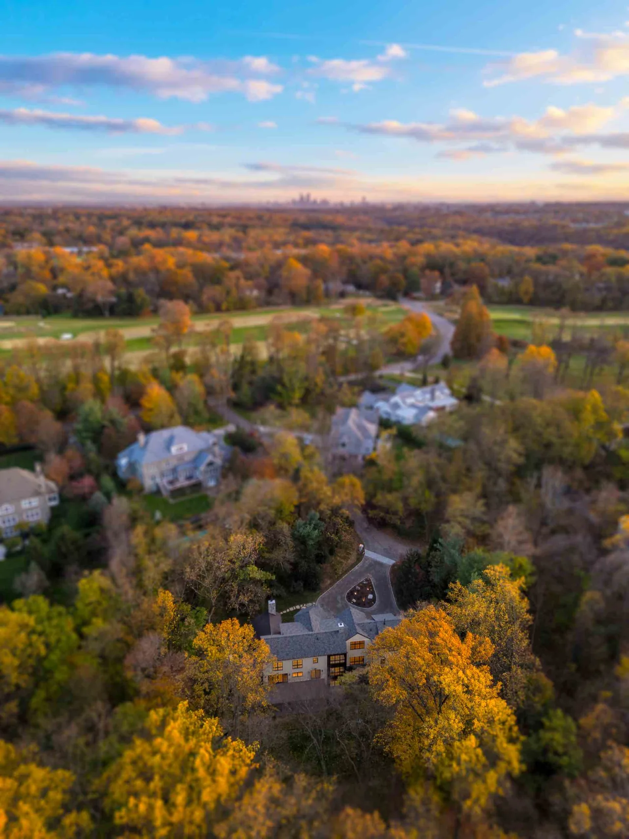 Parkside Sanctuary house nestled among trees with fall colors in a wooded suburban setting.