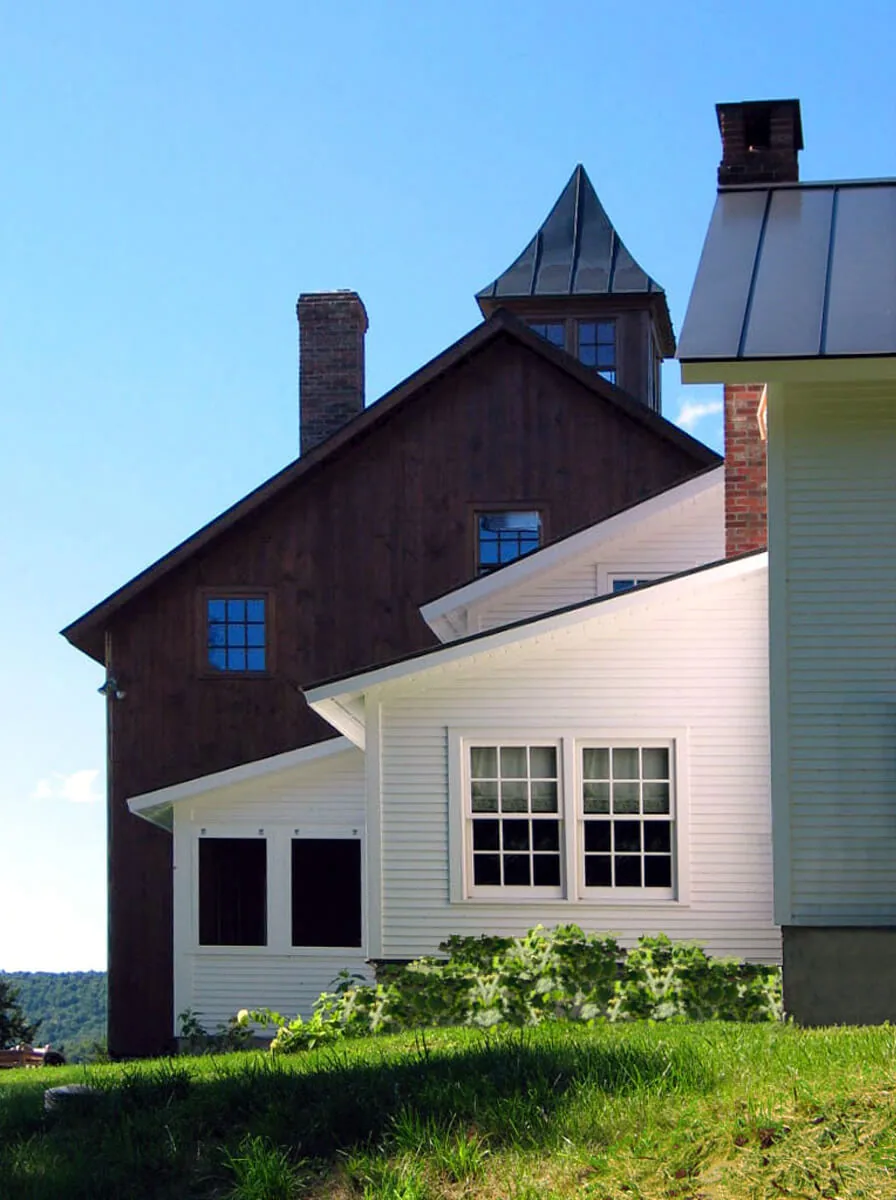 Barn-style home with dark wood siding, white horizontal siding, and prominent brick chimneys.